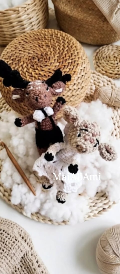 Handmade crocheted amigurumi animals on white fluffy surface surrounded by woven straw baskets and craft materials