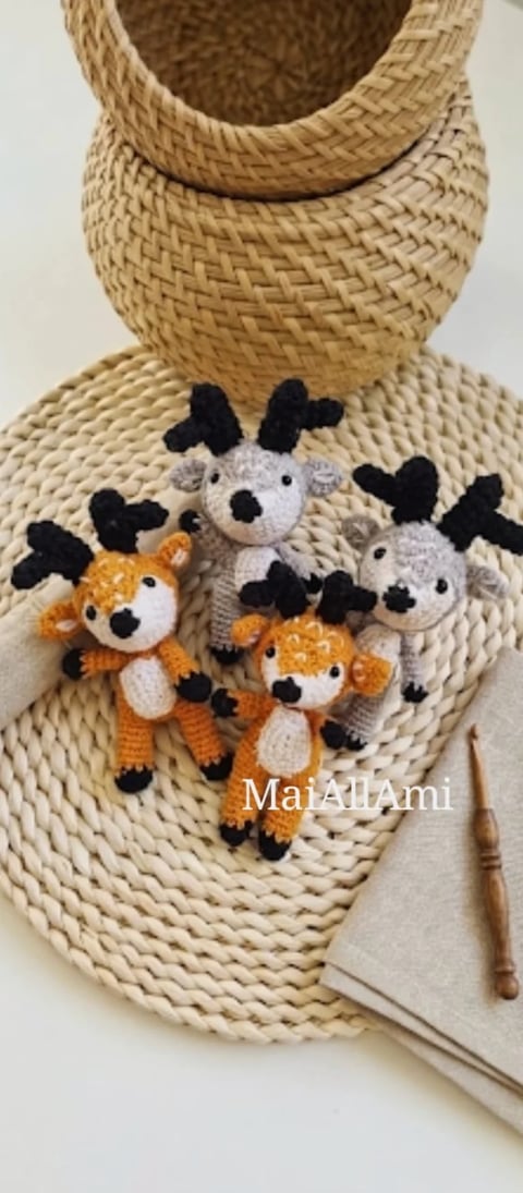 Crocheted cow amigurumi toys in orange and gray on a woven straw basket with crochet hooks and yarn