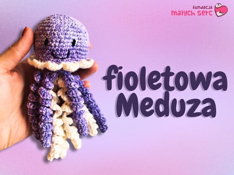 Hand holding a crocheted purple jellyfish toy with white tentacles on a pink background